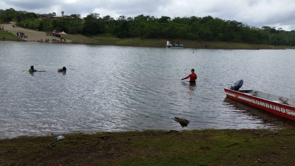 Vista do lago, algumas pessoas dentro dele. | Bombeiros militares foram acionados para resgatar um homem se afogando em lago de Bela Vista de Goiás