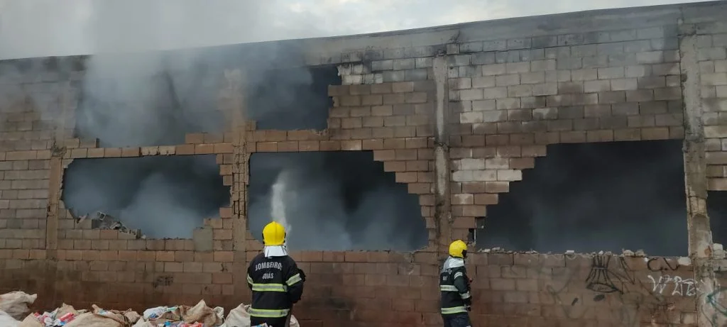 Dois bombeiros apagam chamas em galpão de materiais reclicáveis. | Segundo bombeiros, as equipes se concentraram em combater o foco de incêndio, devido a presença de materiais inflamáveis.