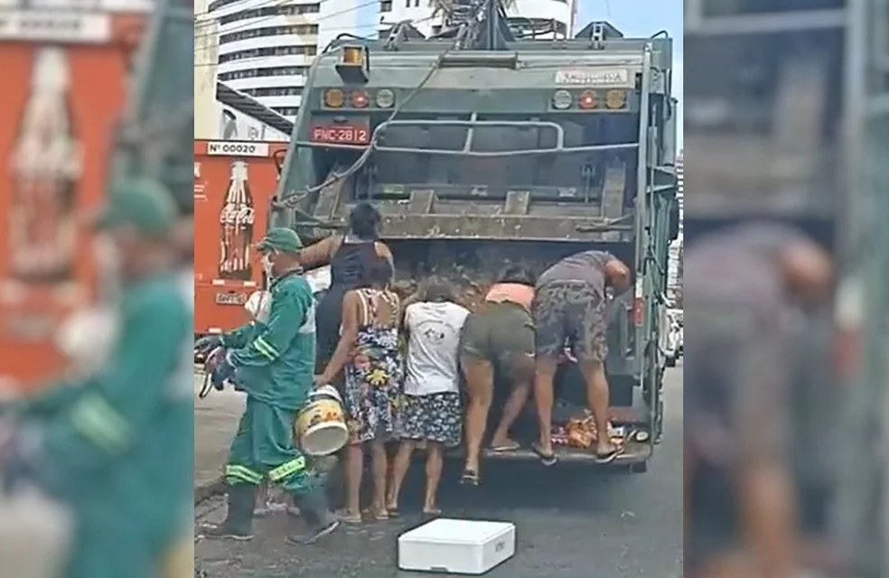 Caminhão de lixo e pessoas ao redor. | Em retrato explícito do crescimento da fome no Brasil, homens e mulheres coletam restos de comida do lixo.