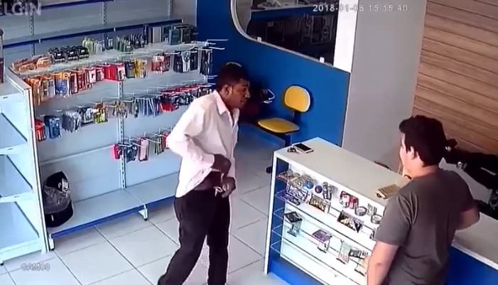 No vídeo, o suspeito leva um tiro do atendente da loja quando este percebe que se trata de um assalto