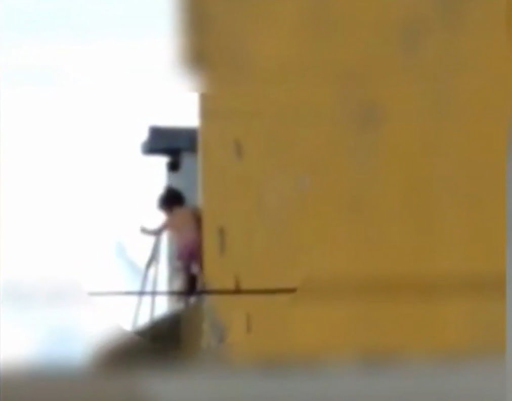 uma criança foi flagrada andando no parapeito de uma janela em um sobrando em Goiânia