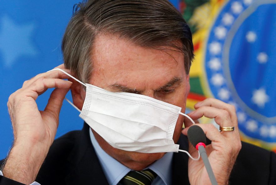 Brazil's President Jair Bolsonaro wearing a protective face masks reacts during a news conference to announce measures to curb the spread of the coronavirus disease (COVID-19) in Brasilia, Brazil March 18, 2020. REUTERS/Adriano Machado