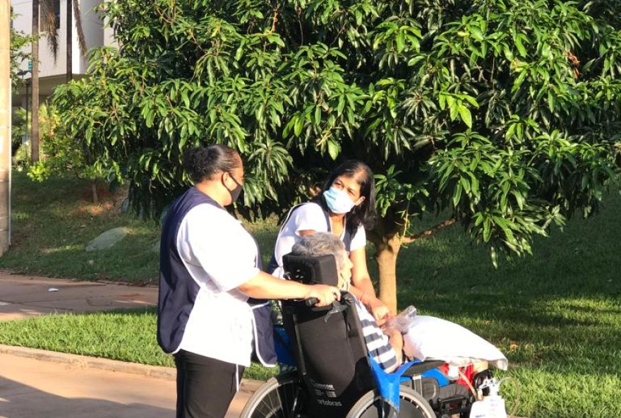 Idoso tomando banho de sol ao lado de cuidadoras, em Brasília. (Foto:  Gislady Mendonça)