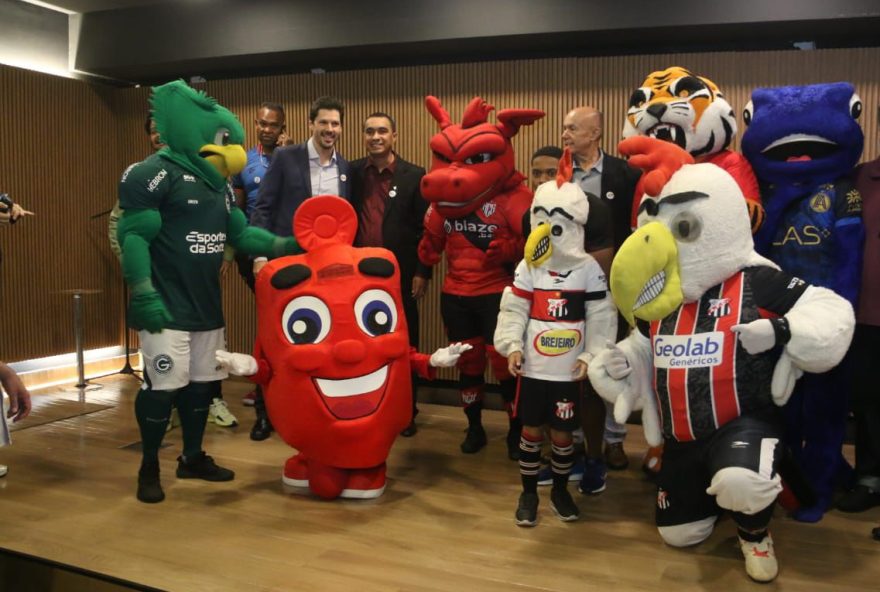 Governador em exercício é abraçado pelo Hemoguinho e mascotes dos clubes goianos.
(Foto: Jota Eurípedes)