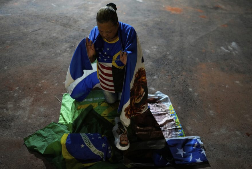 A supporter of Brazil's former President Jair Bolsonaro, prays during a vigil in his support near his home where he is under house arrest, in Brasilia, Brazil, Thursday, Sept. 11, 2025. (AP Photo/Eraldo Peres)