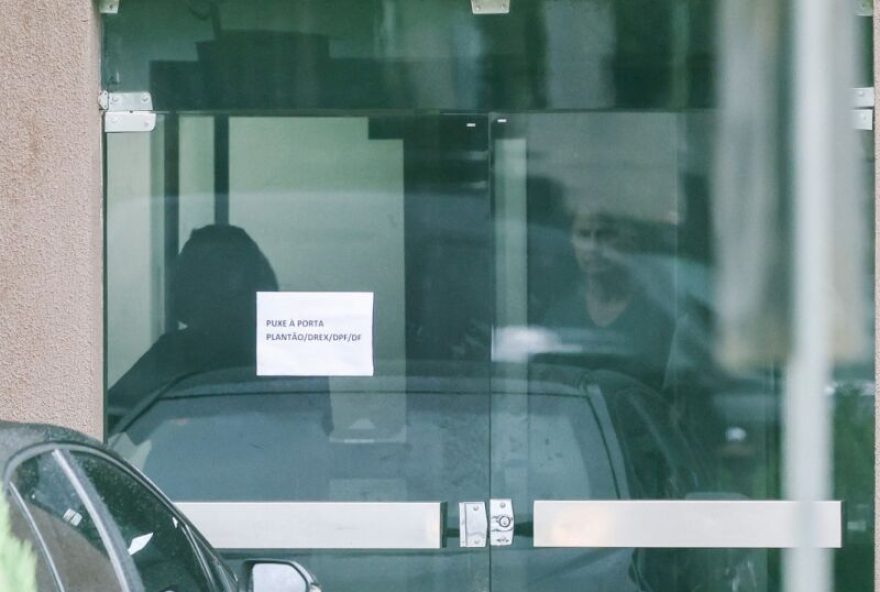 BRAZIL-POLITICS-JUSTICE-COUP-PRISON Brazils former President (20192023) Jair Bolsonaro is seen through the door of the Federal Police headquarters, where he is imprisoned, at the end of former First Lady Michelle Bolsonaros (out of frame) visit in Brasilia, Brazil on November 23, 2025. Bolsonaro, sentenced last September to 27 years in prison for a failed coup attempt but not yet serving his term, was taken into police custody on November 22 after trying to burn the ankle monitor tracking his house arrest, though he later claimed he acted out of paranoia when attempting to disable the device. (Photo by Sergio Lima / AFP)