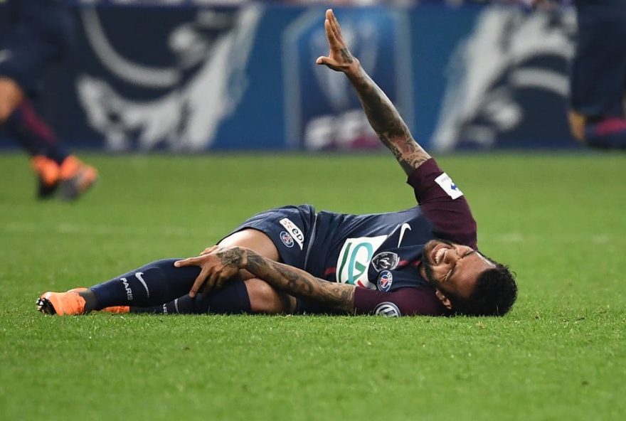 (Foto: AFP) Daniel Alves caído no gramado após a lesão.