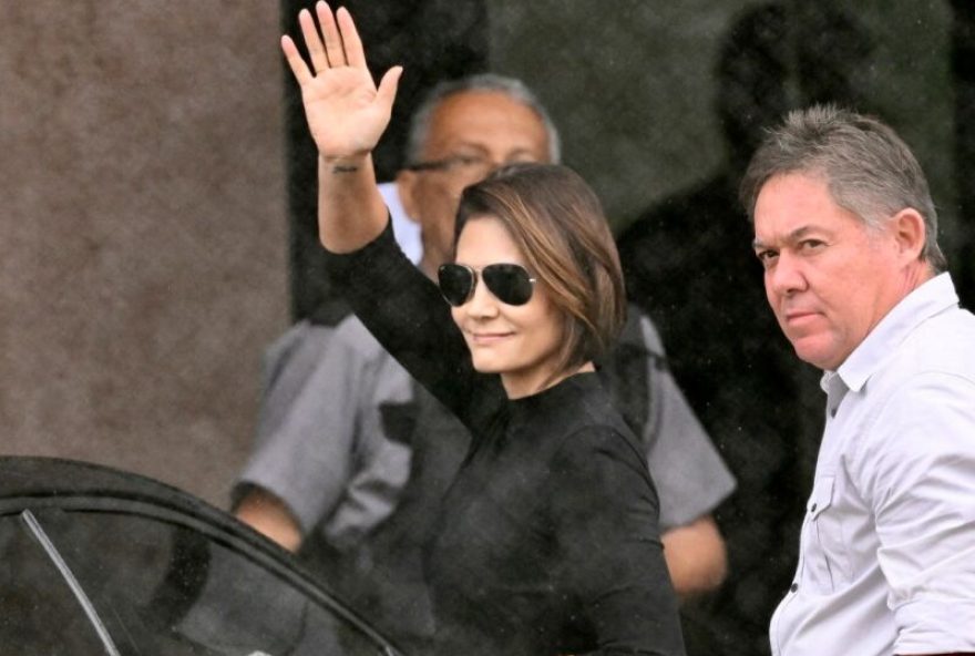 BRAZIL-POLITICS-JUSTICE-COUP-PRISON Michelle Bolsonaro, wife of former Brazil's President (20192023) Jair Bolsonaro waves at supporters on arrival at the Federal Police headquarters, where Bolsonaro is being held, in Brasília, on November 23, 2025. Bolsonaro, sentenced last September to 27 years in prison for a failed coup attempt but not yet serving his term, was taken into police custody on November 22 after trying to burn the ankle monitor tracking his house arrest, though he later claimed he acted out of paranoia when attempting to disable the device. (Photo by Evaristo Sa / AFP)