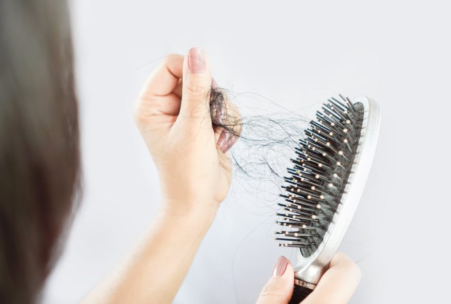 Asian woman hand holding hair loss falling on comb