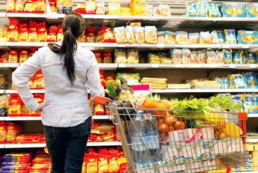 mujer-frente-a-stand-de-supermercado-con-carrito