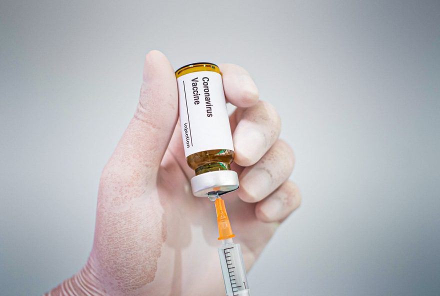 Doctor's hand holding a syringe of covid-19 vaccine and vaccine vial