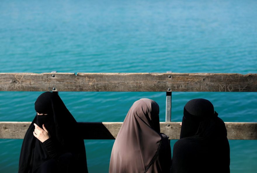 Alaa (L), 21, Amina (C), 24, and Nayab, 18, sit on a dock during a visit to Karlstrup Kalkgrav, a lake near Karlstrup located outside Copenhagen, Denmark, July 19, 2018.  REUTERS/Andrew Kelly    SEARCH 